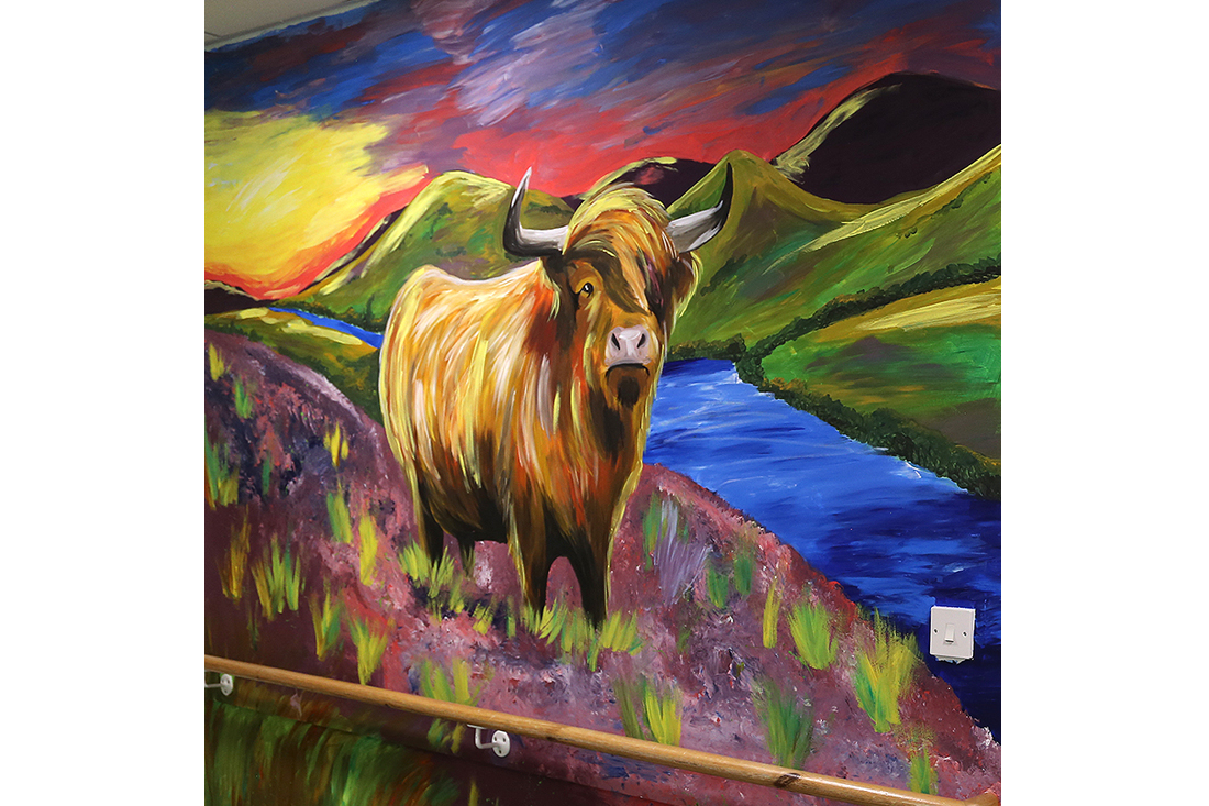 A large, colourful paining of a highland cow on the hallway wall