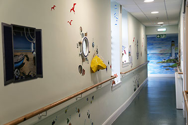 Beach themed hallway with large painting of a lighthouse scene. 